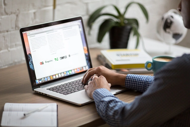 Person sitting at desk in front of laptop Person sitting at desk in front of laptop